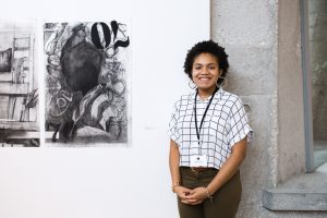 Zoraye Cyrus stands next to one of her works of art being exhibited at the ACA 30th Student Exhibition