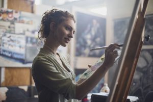 A woman paints on a canvas.