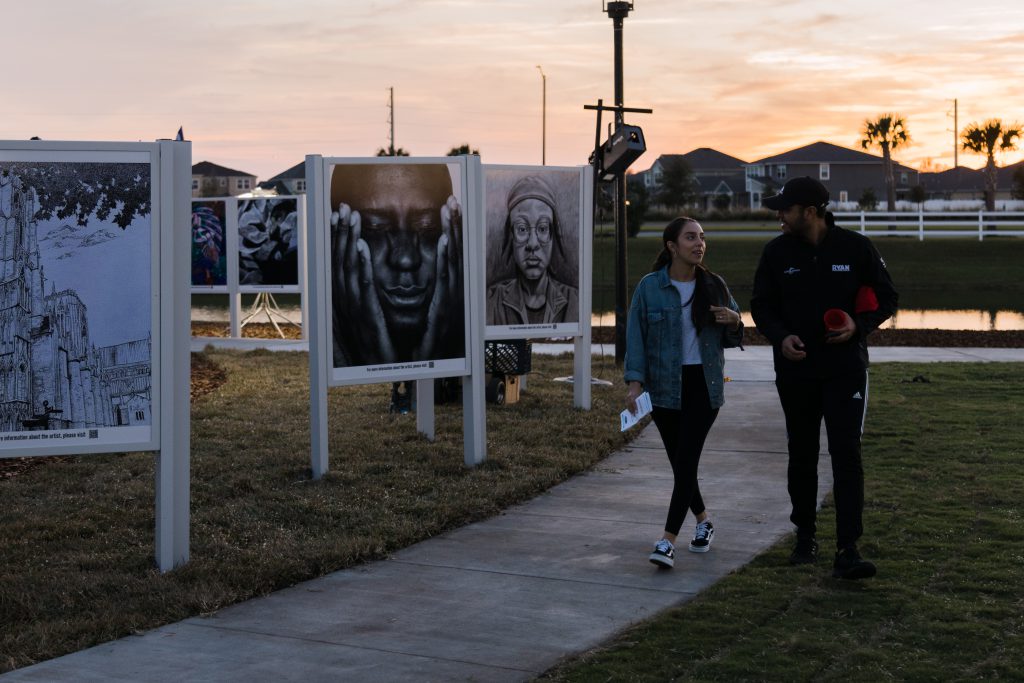 A couple walks past student artwork.