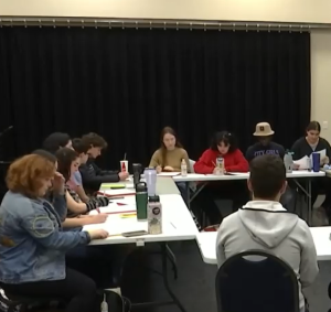 A picture of students sitting at a table looking at their scripts for Home of the Brave.